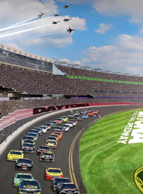 This image shows the Daytona International Speedway with its expansive race track and grandstands filled with spectators. The iconic venue is hosting an exciting car race under a bright sky.