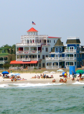  This image shows the charming and peaceful beach of Cape May, with Victorian-style houses in the background and people enjoying the quiet beach atmosphere and picturesque surroundings.