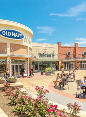 This image shows shoppers at the Tanger Outlets in Atlantic City, with people browsing through stores, enjoying sales on brand-name products, and making purchases in an open-air shopping environment.