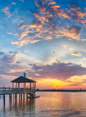 This image shows the peaceful Wrightsville Beach, with soft golden sands, clear blue waters, and people relaxing by the ocean, perfect for a calm beach getaway in Wilmington.