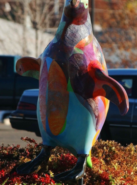 This image shows a brightly painted penguin sculpture in Tulsa, highlighting its playful design and the creativity of local artists.