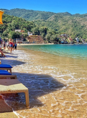 This image shows a picturesque boat ride to Yelapa, with calm waters and lush jungle scenery, as tourists approach the tranquil village known for its beautiful beaches and waterfall.