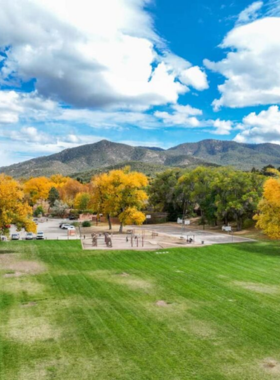 This image shows visitors relaxing at a peaceful park in Santa Fe, with green landscapes, walking trails, and scenic views of the surrounding mountains.