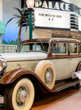 This image shows an exhibit inside the National Automobile Museum in Reno, displaying classic cars from different eras. The collection includes unique vehicles like the 1908 Thomas Flyer and cars from the Pixar Cars franchise, offering an educational and enjoyable experience for visitors.