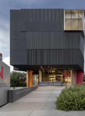 This image shows an art gallery at the Nevada Museum of Art in Reno, showcasing contemporary works from various artists. The museum’s stunning architecture, with its beautiful views of the Sierra Nevada Mountains, provides an immersive space for exploring diverse art forms and exhibits.