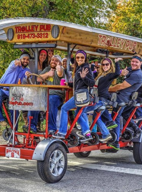 This image shows a lively group pedaling together on a Trolley Pub, enjoying music and drinks while exploring Raleigh’s downtown sights.