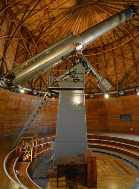 This image shows visitors stargazing at Lowell Observatory under a clear night sky filled with bright stars, with telescopes and observatory domes visible.