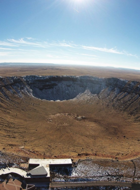 This image shows the vast Meteor Crater, with steep crater walls and a flat interior, highlighting its immense size and natural significance.