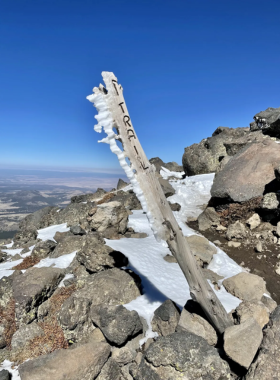 This image shows hikers ascending the trail to Humphreys Peak, with lush alpine meadows, rocky paths, and stunning mountain views.