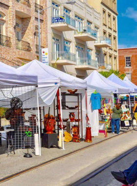 : This image shows visitors exploring a bustling local market in Galveston, with vendors selling handmade crafts, fresh produce, and local seafood, surrounded by colorful stalls and happy shoppers.