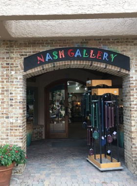 This image shows an art gallery in Hilton Head featuring vibrant paintings, sculptures, and visitors admiring the artwork.