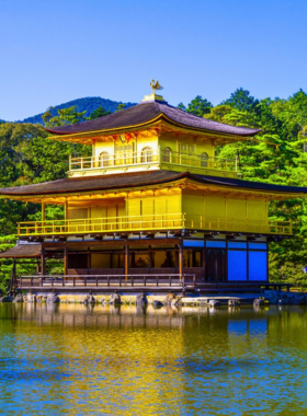 This image shows the Golden Pavilion (Kinkaku-ji) reflected in a tranquil pond, surrounded by lush gardens. The temple's gold leaf-covered exterior shines brightly, creating a serene and picturesque scene in Kyoto.
