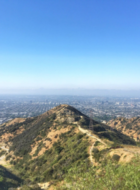 This image shows Runyon Canyon’s scenic hiking trails with views of Los Angeles and the iconic Hollywood sign in the background.