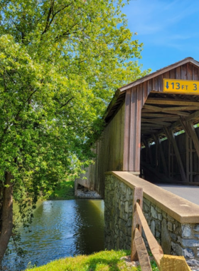 This image shows one of Lancaster County's beautiful covered bridges, framed by lush greenery, symbolizing the area’s historic rural charm and traditional engineering.