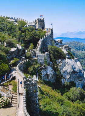 This image shows the fairytale-like Pena Palace in Sintra, with its vibrant colors and impressive architecture, surrounded by lush forests and scenic landscapes.