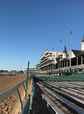 This image shows the historic Churchill Downs racetrack during the Kentucky Derby, with people in the stands, horses racing, and the excitement of one of the world’s most famous horse races.