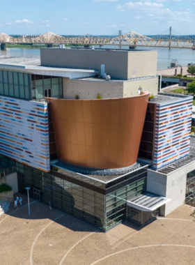  This image shows the Muhammad Ali Center in Louisville, featuring a statue of the boxing legend, with visitors exploring exhibits about his boxing career and contributions to civil rights.