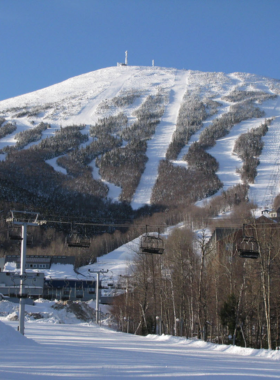 This image shows skiers enjoying the slopes of Sugarloaf Mountain in Carrabassett Valley, Maine, with snow-covered trails and scenic views, making it a top winter destination for outdoor enthusiasts.