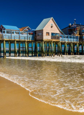 : This image shows the bustling Old Orchard Beach Pier in Maine, with visitors enjoying amusement rides, arcades, and the beautiful seven-mile beach, making it a popular summer destination.