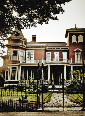 This image shows the eerie exterior of Stephen King’s home in Bangor, Maine, a Victorian-style house surrounded by unusual decorations, often thought to be haunted and a popular stop for fans of the famous horror writer.