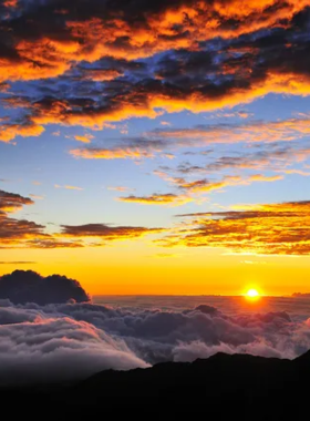 This image shows the breathtaking sunrise over Haleakala National Park in Maui, Hawaii. The view captures the volcanic crater and the surrounding lush landscape, showcasing the beauty of the park’s natural features and the serene atmosphere at dawn.