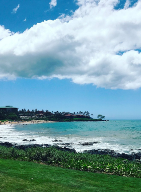 This image shows the peaceful Wailea Beach, known for its clear blue waters and golden sand. The photo captures visitors enjoying swimming, snorkeling, and relaxing under the sun, with luxury resorts providing a backdrop to the stunning coastal landscape.