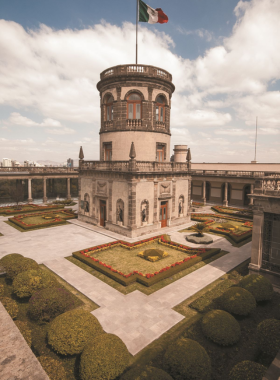 This image shows Chapultepec Castle atop a lush hill, surrounded by panoramic city views. The majestic structure reflects Mexico’s historical grandeur, with visitors exploring its gardens and learning about its role as a royal residence and museum.