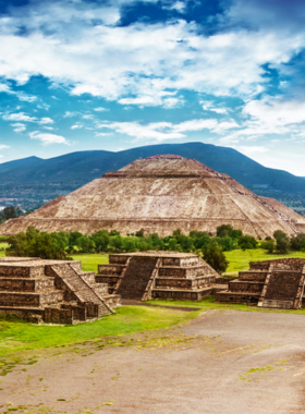 This image shows the majestic Teotihuacan Pyramids, with the Pyramid of the Sun rising prominently against a clear sky. Tourists climb its steps to enjoy panoramic views, exploring the historical Avenue of the Dead and ancient temples nearby.