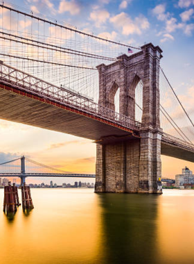 This image shows the Brooklyn Bridge with pedestrians and cyclists crossing over it. The bridge offers stunning views of downtown Manhattan, the East River, and Brooklyn, making it a must-visit NYC landmark with a rich history and picturesque views.