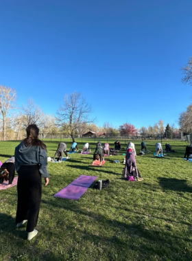 "This image shows a peaceful outdoor yoga session by Boulder Creek, with participants practicing poses on mats surrounded by trees and the calming sound of flowing water. The serene natural environment provides the perfect setting for mindfulness and relaxation."