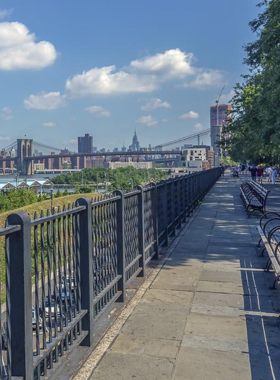 This image shows that the Brooklyn Heights Promenade is a peaceful waterfront path with stunning views of the Manhattan skyline, the Statue of Liberty, and a relaxing spot to enjoy the scenic surroundings.