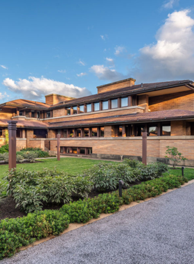 This image shows the stunning exterior of Frank Lloyd Wright’s Martin House, showcasing the open space design, use of natural light, and beautiful gardens, symbolizing the architect’s innovative vision for residential architecture.