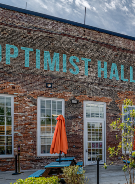 This image shows the vibrant and bustling food vendors at Optimist Hall, where visitors can explore a wide variety of delicious food options. The lively atmosphere features local eateries serving everything from gourmet tacos to artisanal sandwiches.