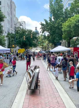 This image shows Main Street in Columbia, showcasing its vibrant atmosphere with historic buildings, bustling shops, and pedestrians enjoying the lively environment. The street captures the city's unique blend of history and modern life.