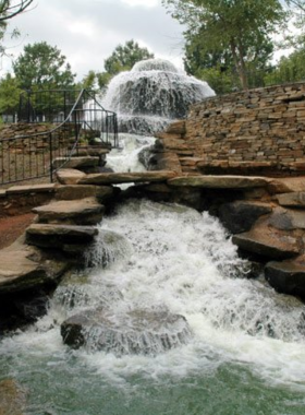 This image shows Finlay Park in Columbia, featuring lush green spaces, scenic waterfalls, and families enjoying the outdoors. The park is a serene escape within the city, ideal for relaxation and picnics.