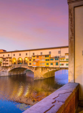 This image shows the iconic Ponte Vecchio bridge, spanning the Arno River. The bridge is lined with jewelry shops, offering a unique shopping experience with picturesque views of the river and Florence’s architecture.