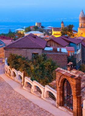 This image shows the romantic town of Sighnaghi, with cobblestone streets, terracotta rooftops, and a panoramic view of the Alazani Valley and Caucasus Mountains.