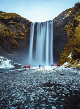 This image shows the powerful Skogafoss waterfall cascading over 60 meters with lush green surroundings and a rainbow in the mist, showcasing one of Iceland’s most iconic waterfalls.