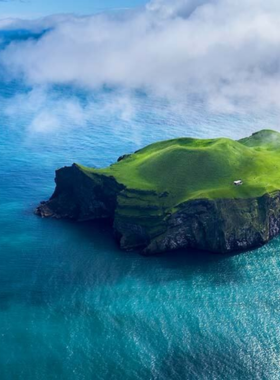 This image shows the volcanic landscape of Heimaey Island in Iceland, with remnants of a past volcanic eruption and beautiful coastal views, offering a unique glimpse into Iceland's volcanic history.