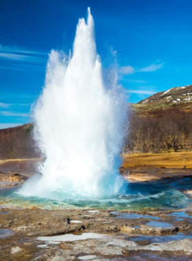 This image shows the Strokkur geyser erupting with hot water soaring into the air in the Geysir geothermal area in Iceland, an exciting natural spectacle for visitors.