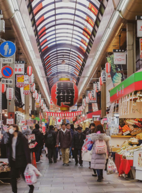 This image shows the bustling Kuromon Market in Osaka, with food stalls selling fresh seafood, sushi, and street food such as takoyaki and kushikatsu. The market is a must-visit for food lovers, offering a variety of local delicacies and a vibrant atmosphere.