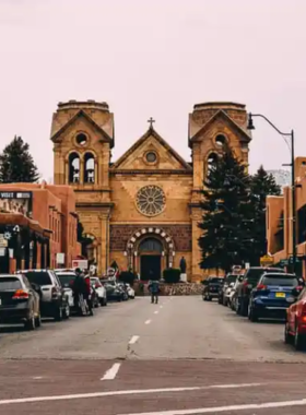 This image shows the charming Santa Fe Plaza, with adobe-style architecture and vibrant cultural life. People are seen enjoying the live music and browsing local food markets, surrounded by art galleries that reflect the rich history and culture of Santa Fe.