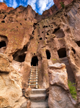 This image shows visitors hiking through the scenic Bandelier National Monument, exploring ancient cliff dwellings and petroglyphs. The image highlights the stunning natural landscape and cultural history of the Ancestral Pueblo people.