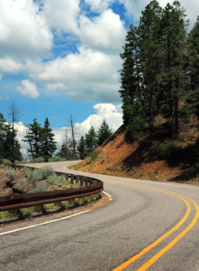 This image shows a car driving along one of New Mexico’s scenic byways, passing through picturesque desert landscapes and small charming towns. The image captures the beauty of the state's natural surroundings and diverse terrain.