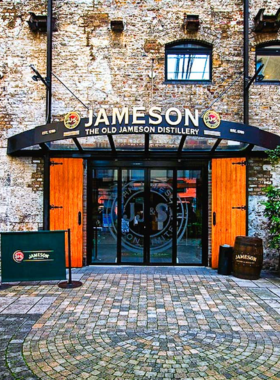 This image shows visitors inside the Jameson Distillery in Dublin, participating in whiskey-tasting tours and learning about the history of Irish whiskey-making. The image highlights traditional barrels and distilling equipment.