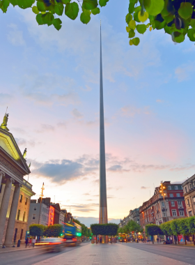 This image shows the Spire of Dublin, a modern stainless steel monument standing tall on O’Connell Street. Visitors are walking around the area, taking photos, and enjoying the busy city vibe surrounding this iconic landmark.