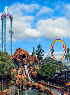 This image shows a roller coaster at Knott’s Berry Farm with riders speeding down a steep track, arms raised in excitement. The bright yellow and red coaster contrasts with the clear blue sky in the background. Visitors waiting in line can be seen watching the ride with anticipation. The image captures the energy, thrill, and fun that Knott’s Berry Farm offers for adventure lovers and families.