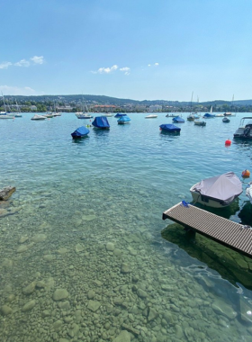 This image shows visitors enjoying a sunny day at Seebad Enge in Zurich. The lakeside swimming area is a popular destination for relaxation, wellness, and swimming, offering stunning views of Lake Zurich and the surrounding mountains.