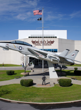 This image shows the National Naval Aviation Museum’s exhibit hall, featuring rows of historic aircraft and aviation artifacts. Visitors walk through the gallery, admiring the impressive collection of planes from various eras, including World War II and modern military jets, showcasing the evolution of naval aviation.