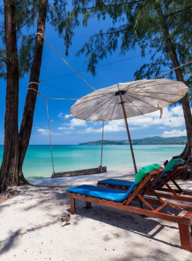 This image shows the serene Bangtao Beach during sunset, with its golden sands, calm waters, and scenic view, offering a relaxing beach experience for visitors.